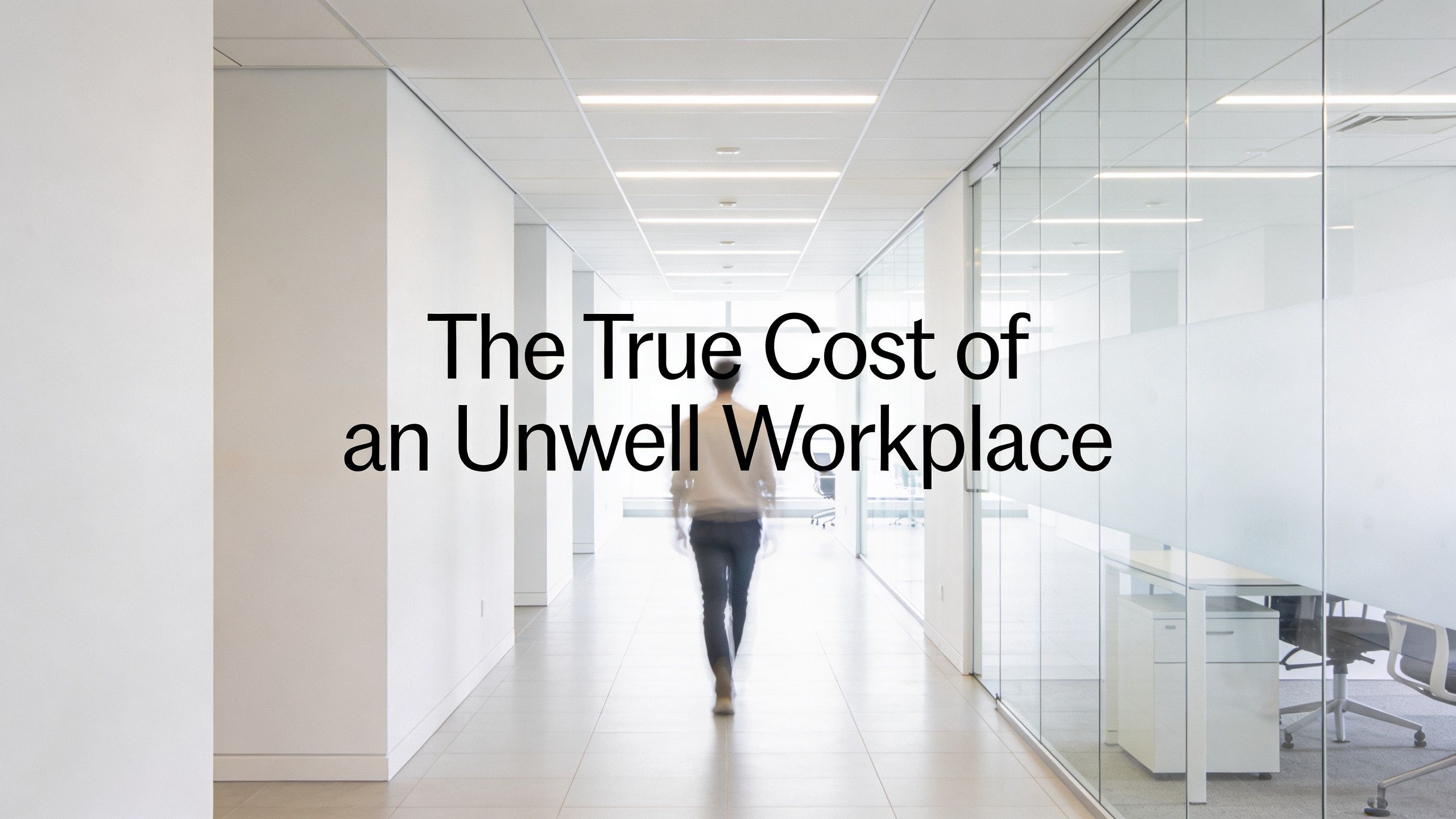 A blurred figure walks down a bright, modern office hallway with glass partitions on both sides.